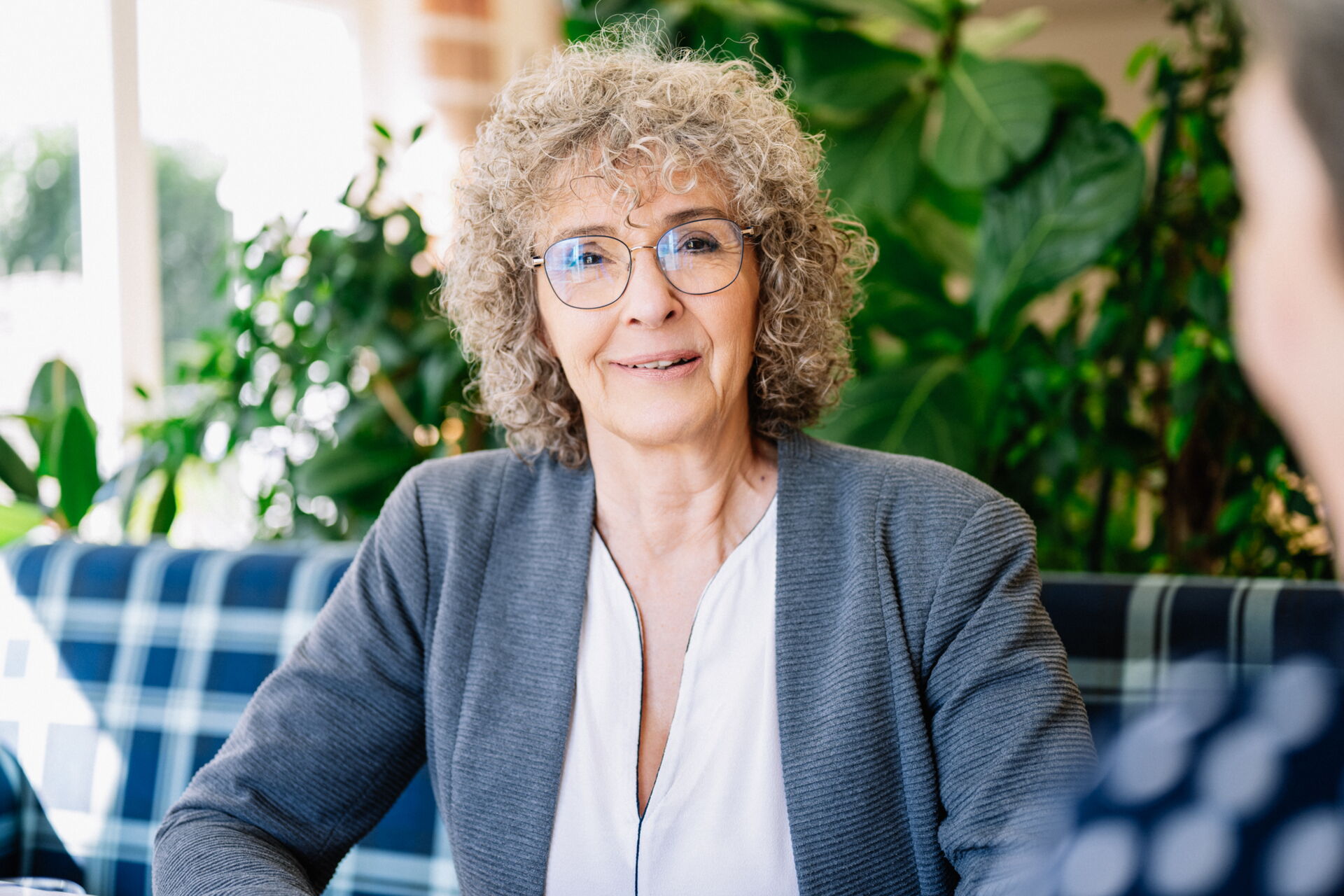 Aufnahme von der Frau Anke Hauschulz vor einer grünen Pflanze- mehr als nur Makler- & Finanzberatung