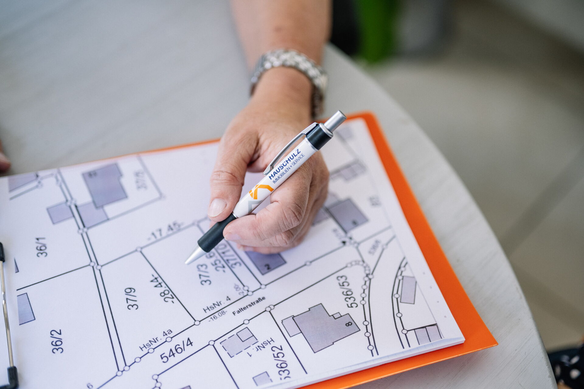 Hand mit Hauschulz Immobilien Service Stift auf einem Grundriss. Symbol für Planung und Beratung durch Hauschulz.